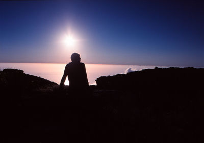 Rear view of silhouette man looking at sunset