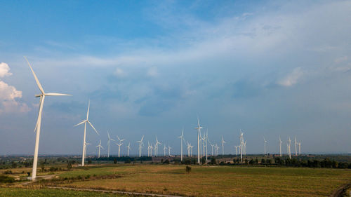 Scenic view of windmills on field against sky