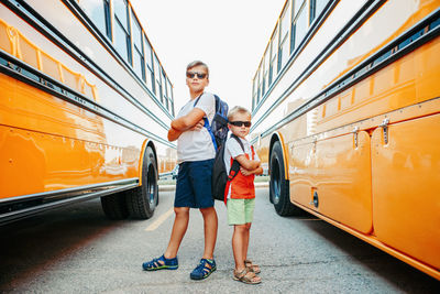 Full length of boys standing by bus