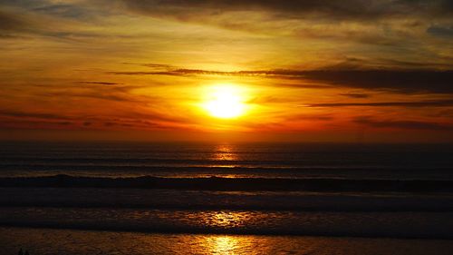 Scenic view of sea against dramatic sky during sunset