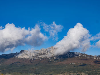 Smoke emitting from volcanic mountain against blue sky