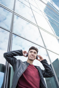 Portrait of young man standing against window