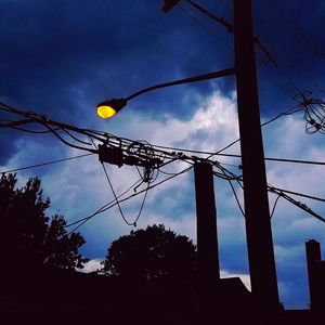 Low angle view of silhouette electricity pylon against sky