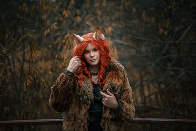 Portrait of woman standing against tree during winter