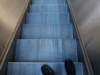 Low section of man standing on escalator