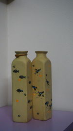 Close-up of empty bottles on table against wall