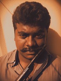 Close-up portrait of young man making face against wall