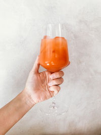 Close-up of hand holding glass with kombucha agings concrete wall