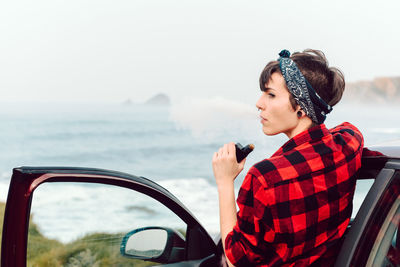 Young woman looking away in sea against sky