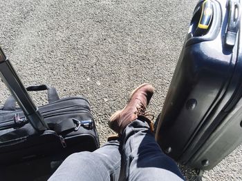 Low section of man with suitcases on road