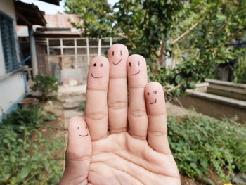 Cropped image of hand with smiley face in yard