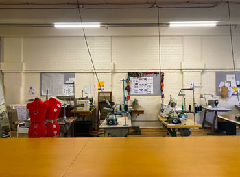 Interior of building sewing workshop, fluorescent lights, industrial sewing machines, cutting table