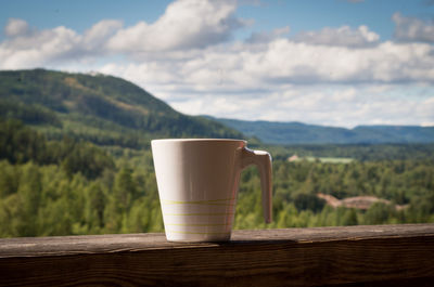 Close-up of drink on railing against mountains