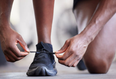 Low section of man tying shoelace