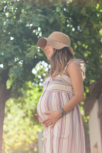 Side view of a young woman standing against plants