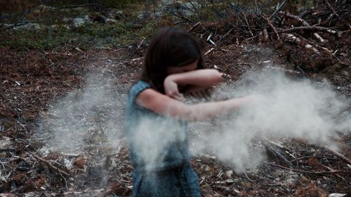 Girl playing with powder on field at forest