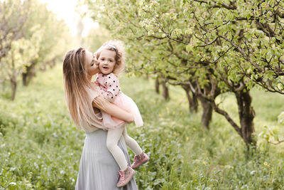 Mother kissing daughter standing on grass