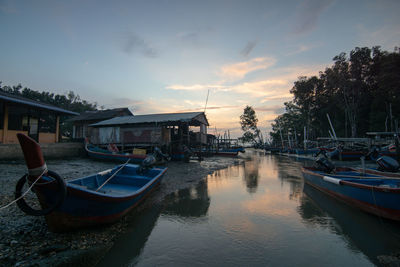 Boats moored in canal at sunset