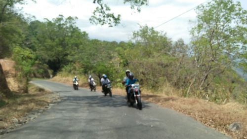 Rear view of people riding bicycle on road