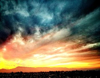 Silhouette landscape against dramatic sky during sunset