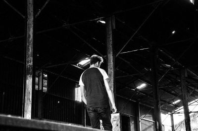 Rear view of man walking on illuminated ceiling