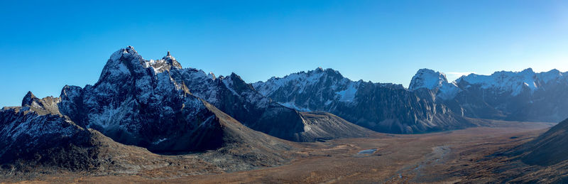 Panoramic view of snowcapped mountains against clear blue sky