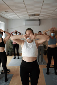 Group of women practicing pilates exercises in class with masks