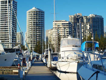 Sailboats moored at harbor against buildings in city