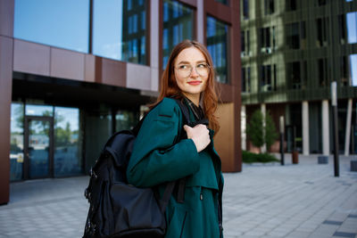 Portrait of young woman standing in city