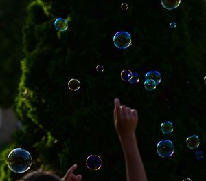 Cropped arm raised amidst bubbles in mid-air