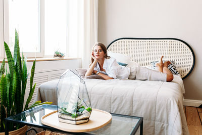 Young woman using mobile phone while sitting on bed