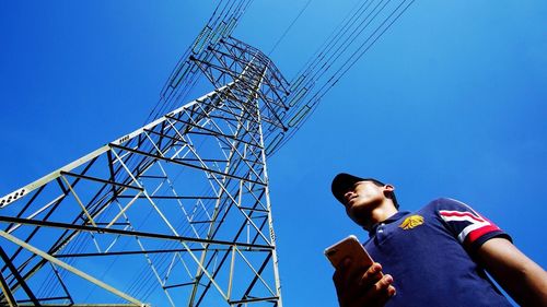 Low angle view of electricity pylon against clear blue sky