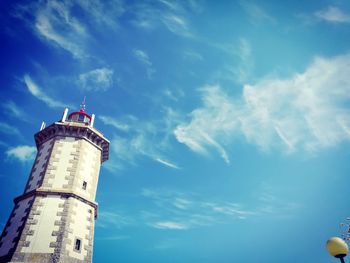 Low angle view of lighthouse by building against sky