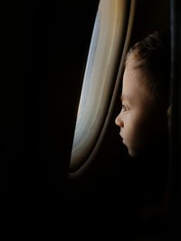 Close-up of boy looking through airplane window