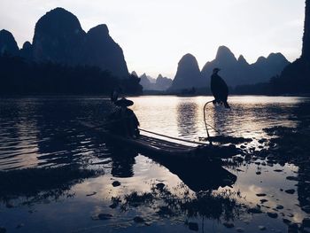 Man with two cormorants on boat