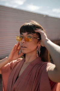 Portrait of woman holding sunglasses outdoors