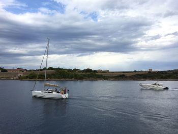 Boat in calm sea against cloudy sky