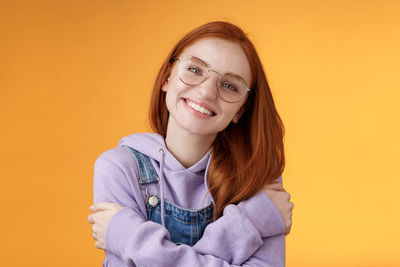 Portrait of a smiling young woman against yellow background