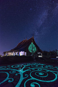 Low angle view of illuminated temple against star field at night