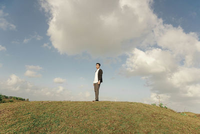 Rear view of man standing on field against sky