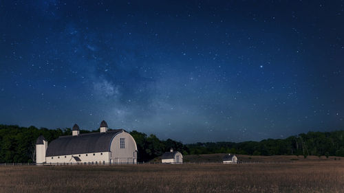 Three white barns in a far away farm land at night with stars