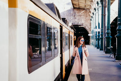 Woman walking by train on railroad station platform