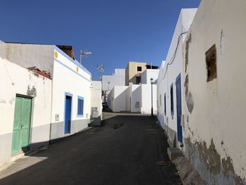 Alley amidst buildings against blue sky