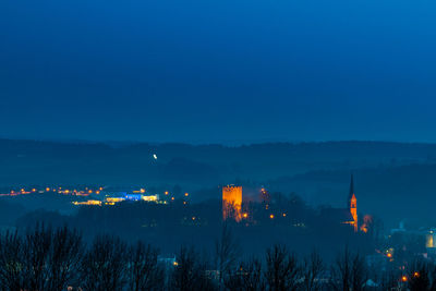 Illuminated buildings against clear sky at dusk