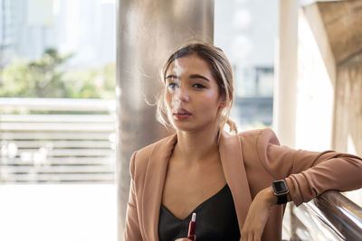 Young woman smoking while standing outdoors