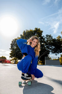 Cheerful caucasian woman with blonde hair skating in urban setting