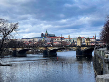 Arch bridge over river against sky in city