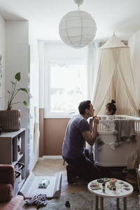 Father playing with male toddler inside crib at home