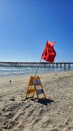 Lifeguard hut on beach against clear blue sky