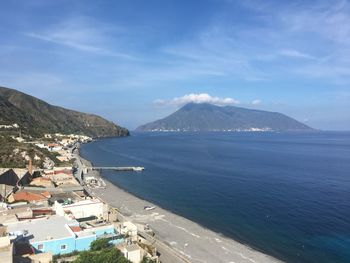 High angle view of sea and mountains against blue sky